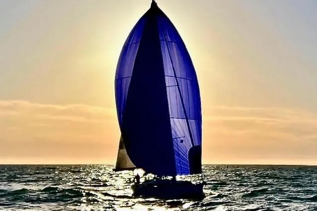 White Rose Yacht Photos Pics Sailing yacht Sabre 426 (2003) with blue spinnaker at sunset on the ocean.