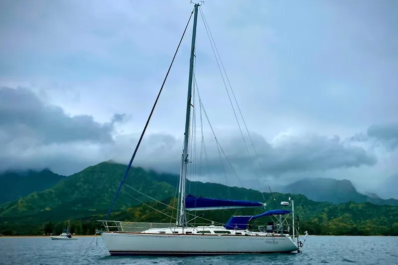 White Rose Yacht Photos Pics Sailboat Sabre 426 (2004) on water with mountainous backdrop and cloudy sky.