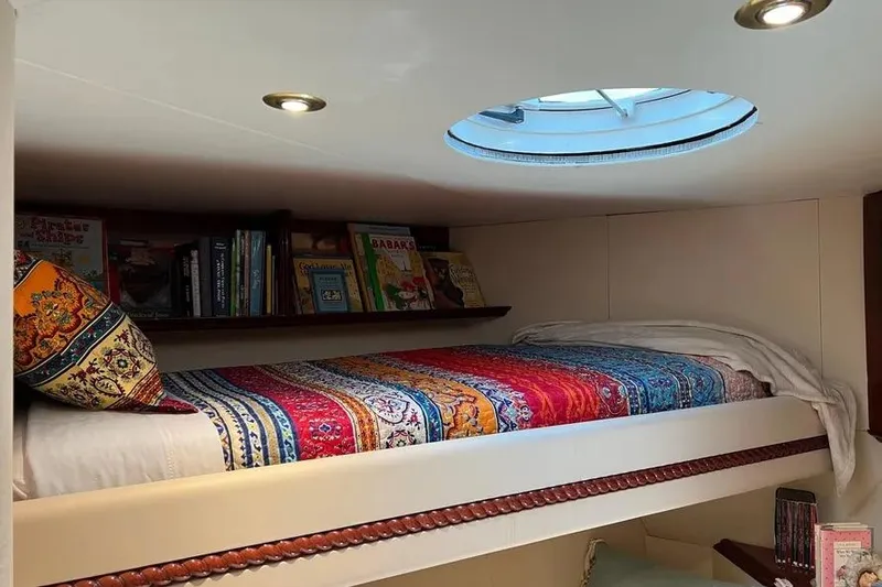  Yacht Photos Pics Cozy 2004 Lazzara SC Motor Yacht cabin with colorful bedding and books under a skylight.