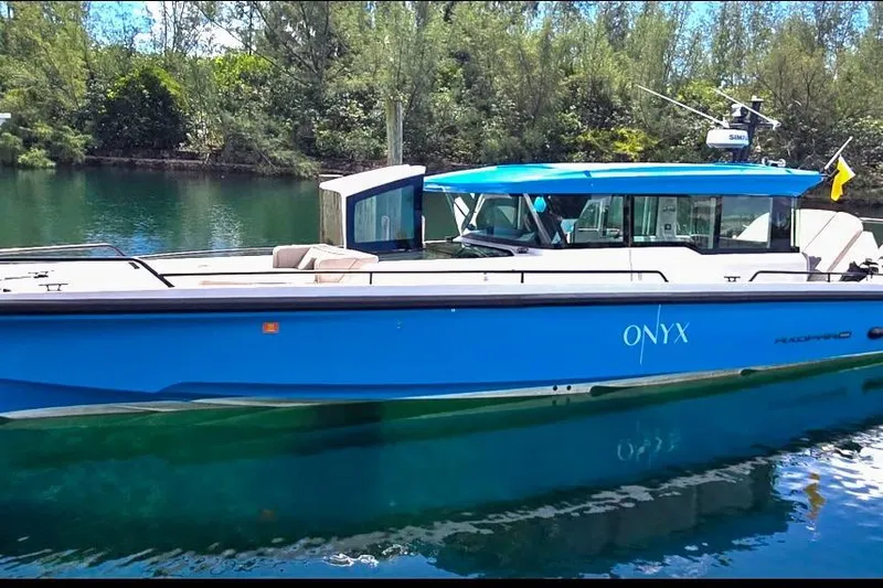  Yacht Photos Pics 2024 Axopar 37XC CROSS CABIN boat in blue, docked on a serene waterway.