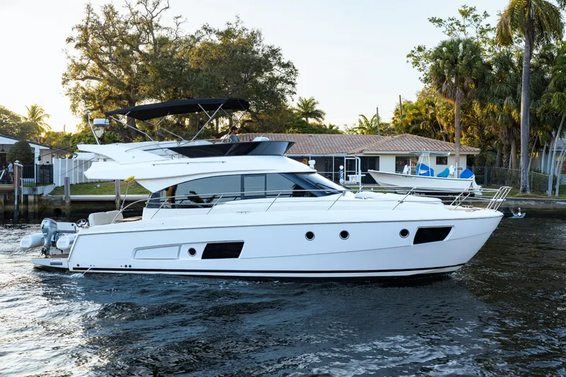  Yacht Photos Pics 2013 Bavaria Virtess 420 Fly yacht cruising on a serene waterway, surrounded by lush greenery.