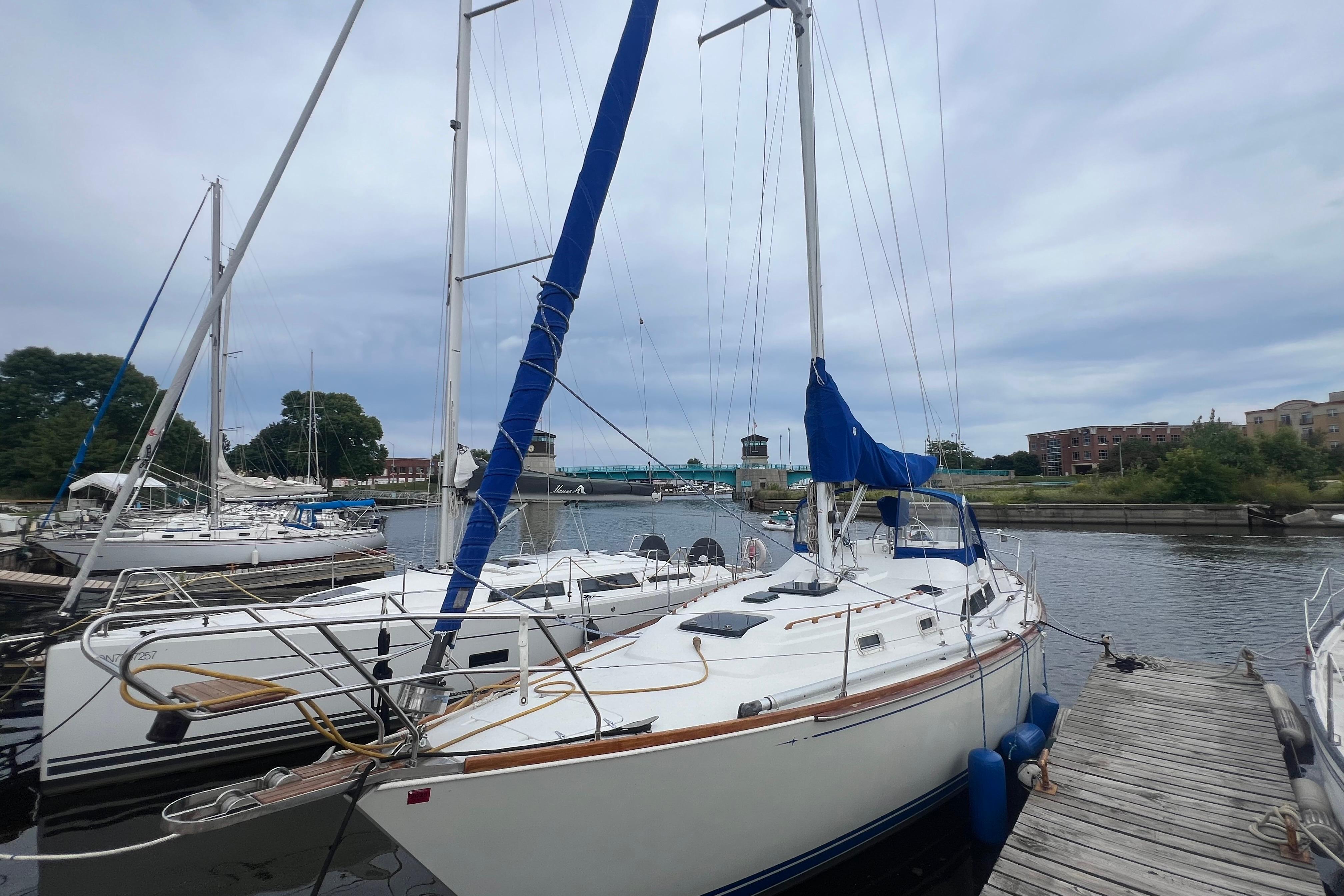 1985 C&C Landfall 39 sailboat docked at a marina with blue sail covers.