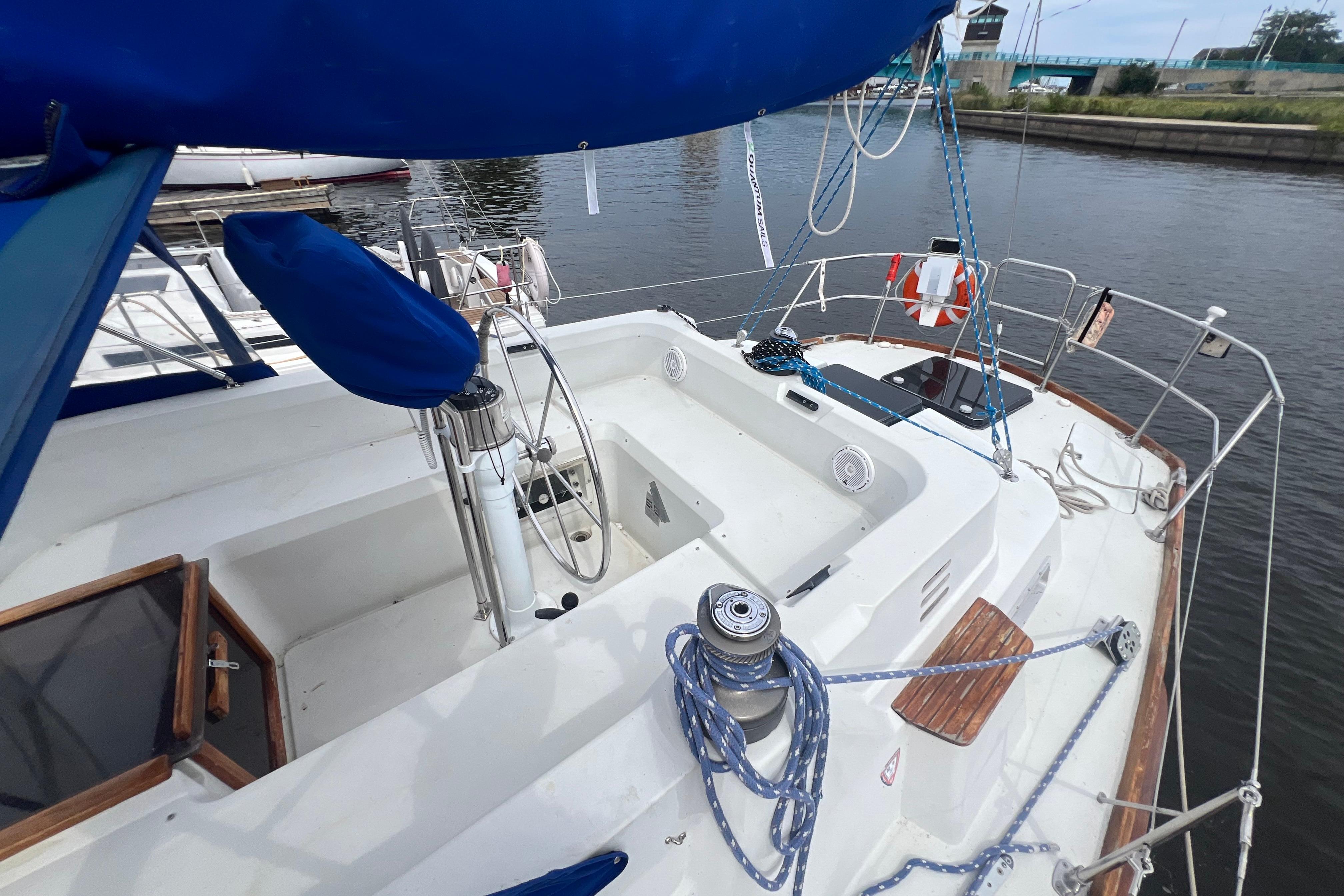 1985 C&C Landfall 39 sailboat cockpit with blue cover, docked by a calm waterway.