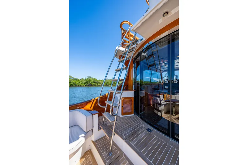 Vera North Yacht Photos Pics 2021 Hinckley Talaria yacht deck with ladder, glass doors, and scenic water view.