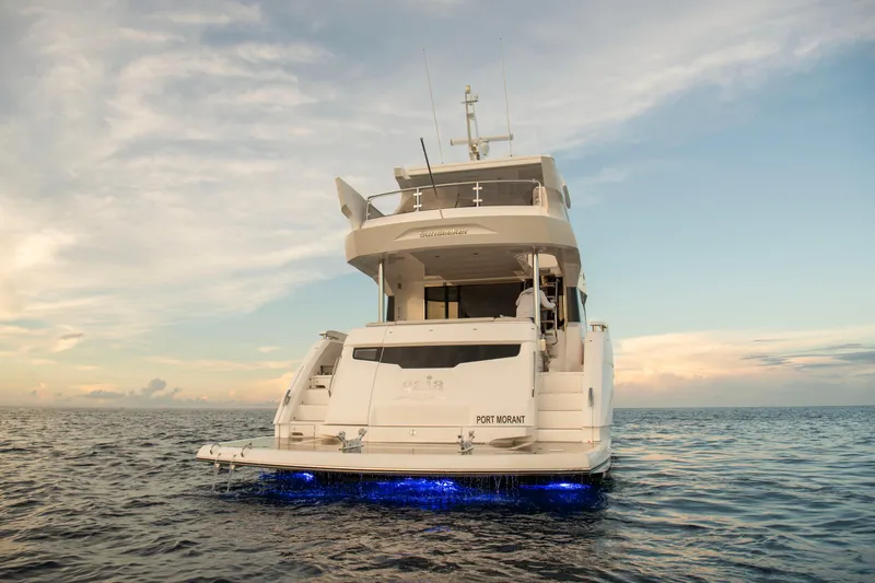 Gaia Yacht Photos Pics 2022 Sunseeker Manhattan 68 yacht on open water at sunset, rear view.