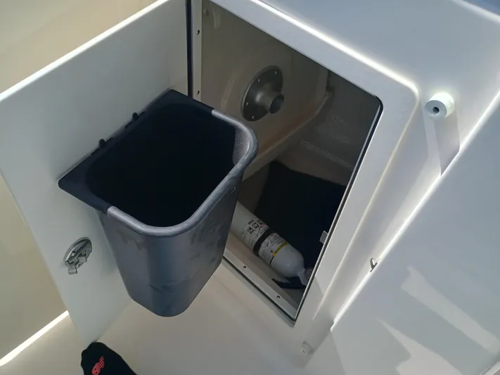 257-155 Yacht Photos Pics 2025 Robalo R257 Dual Console storage compartment with trash bin and fire extinguisher.