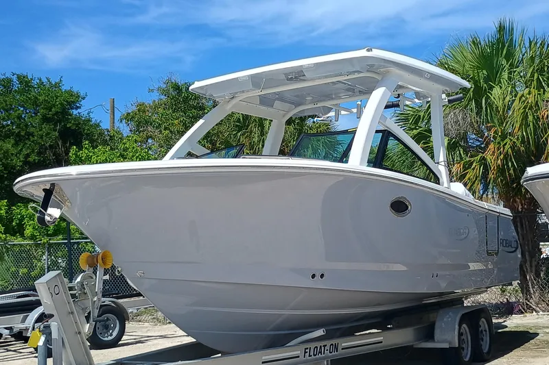 257-155 Yacht Photos Pics 2025 Robalo R257 Dual Console boat on trailer, parked outdoors under blue sky.