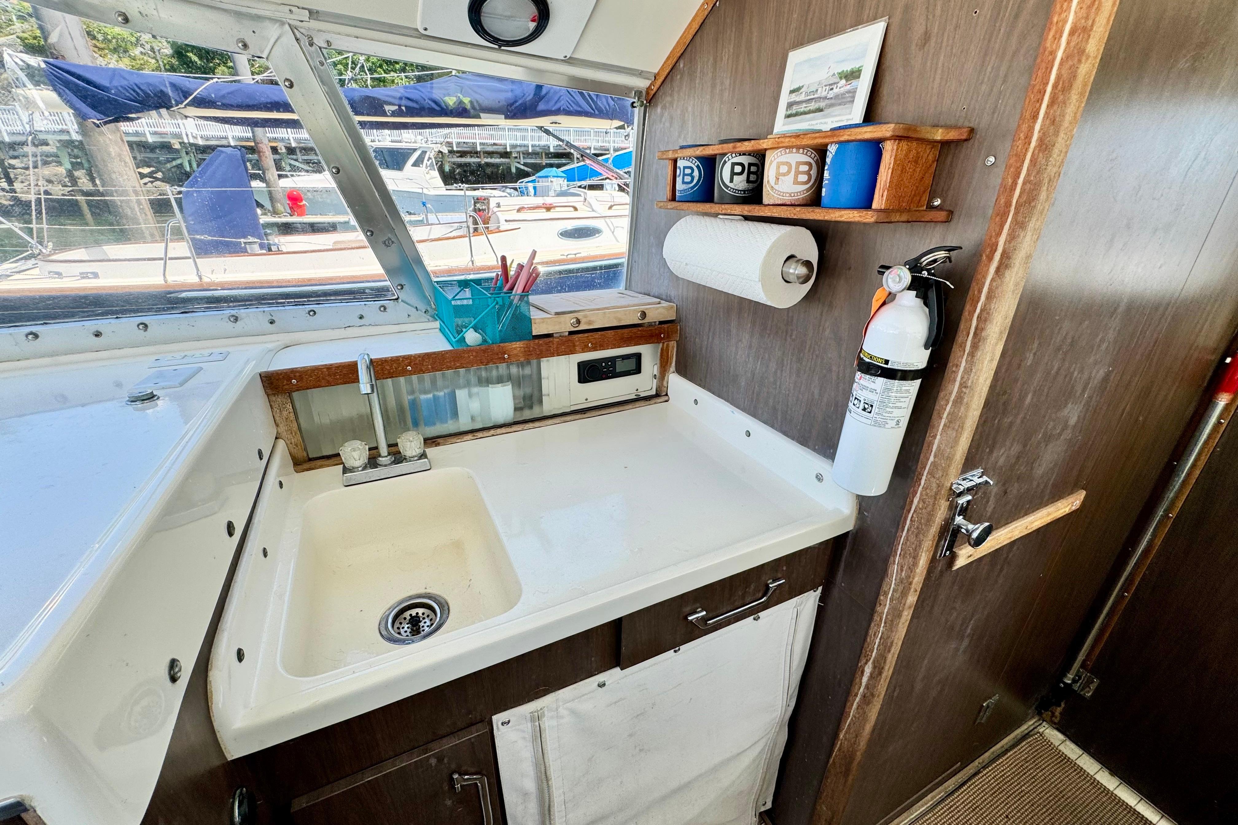 1973 Bertram 31 Flybridge Cruiser interior with sink, storage, and window view of marina.