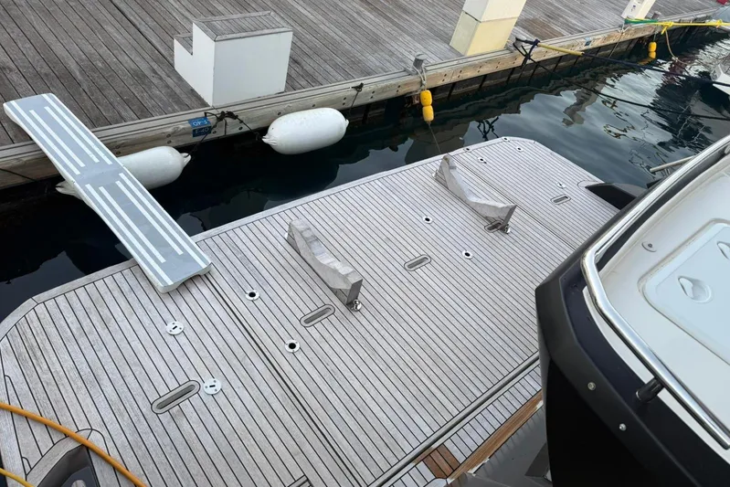 3775 Yacht Photos Pics Sleek 2019 Absolute 62 Fly yacht docked with wooden deck and boarding ramp.