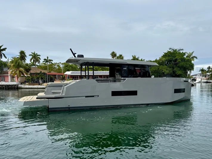  Yacht Photos Pics 2023 De Antonio Yachts D50 Coup&eacute; cruising on a serene waterway with lush greenery.
