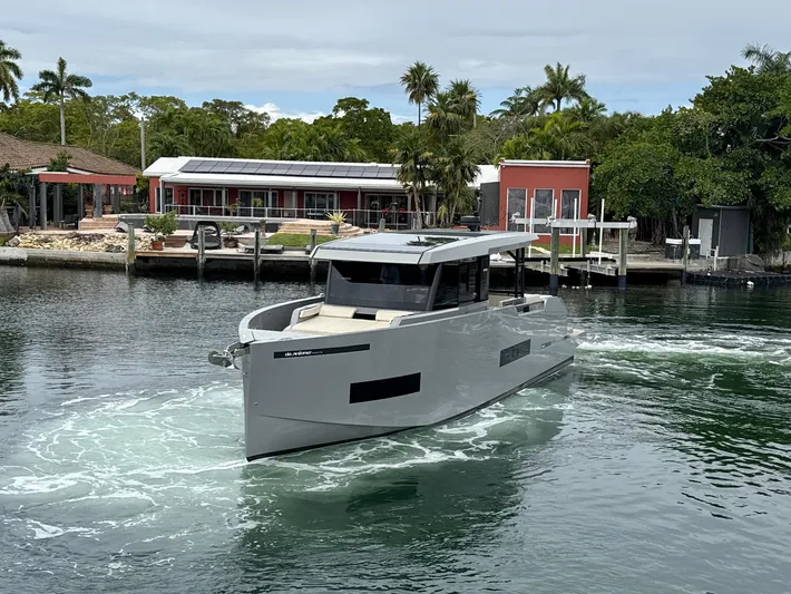  Yacht Photos Pics 2023 De Antonio Yachts D50 Coup&eacute; cruising near a modern waterfront property.