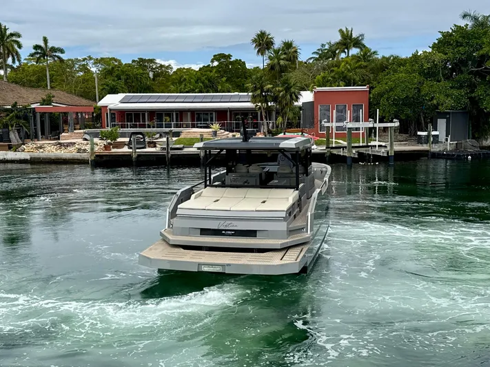  Yacht Photos Pics 2023 De Antonio Yachts D50 Coup&eacute; cruising near waterfront homes with lush greenery.