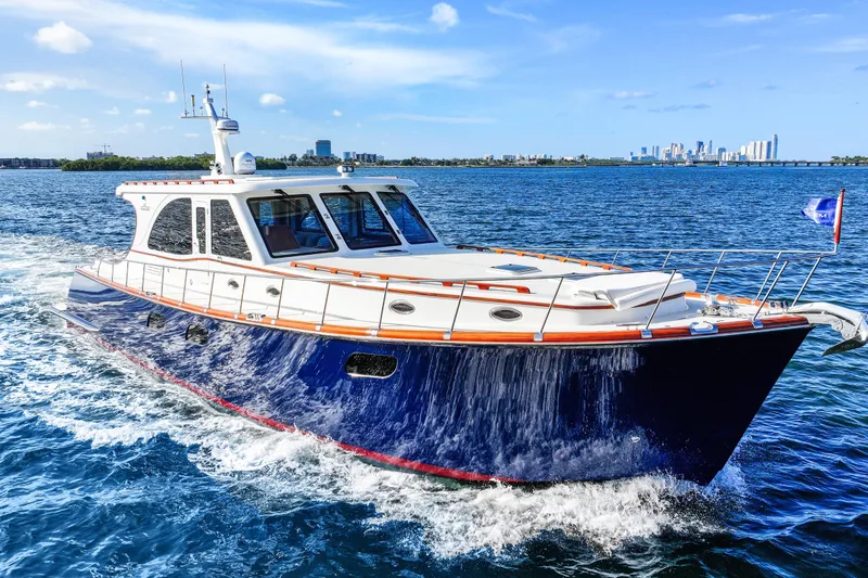 Bebe Deux Yacht Photos Pics 2023 Vicem 65 Classic yacht cruising on blue ocean with city skyline in background.