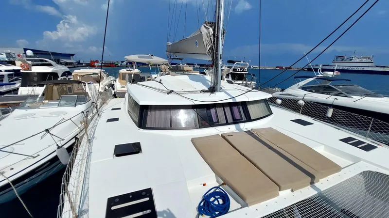  Yacht Photos Pics 2018 Fountaine Pajot Saona 47 catamaran docked in a marina, featuring spacious deck and sails.