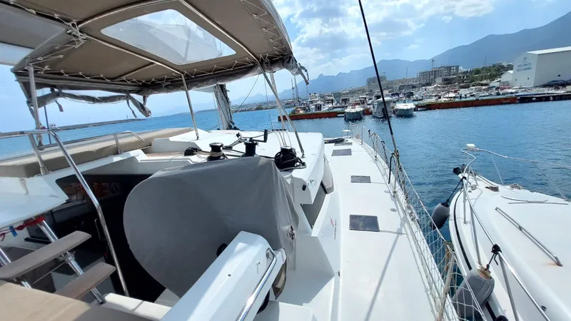  Yacht Photos Pics 2018 Fountaine Pajot Saona 47 catamaran docked at marina, sunny day, scenic mountain backdrop.