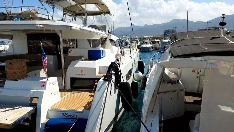  Yacht Photos Pics 2018 Fountaine Pajot Saona 47 catamaran docked in a marina with scenic mountain backdrop.