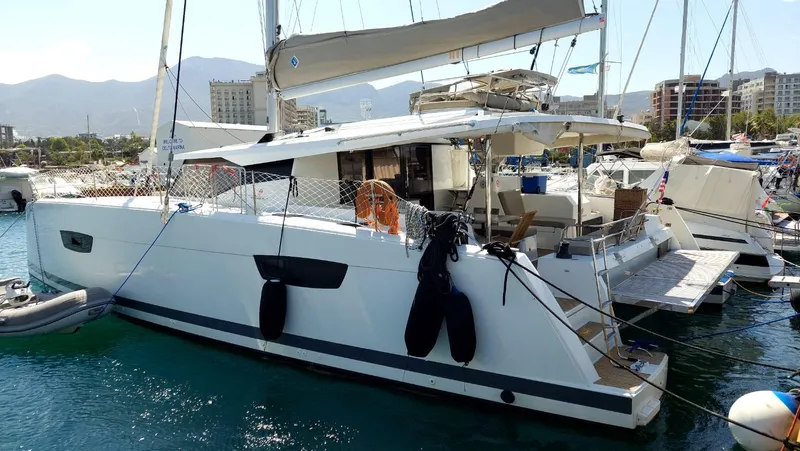  Yacht Photos Pics 2018 Fountaine Pajot Saona 47 catamaran docked in a marina, with mountains in the background.