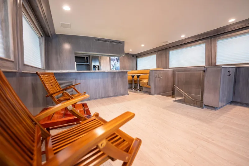 Hatt's Off Yacht Photos Pics Luxurious interior of 1998 Hatteras 74 Cockpit Motor Yacht with wooden chairs and modern decor.