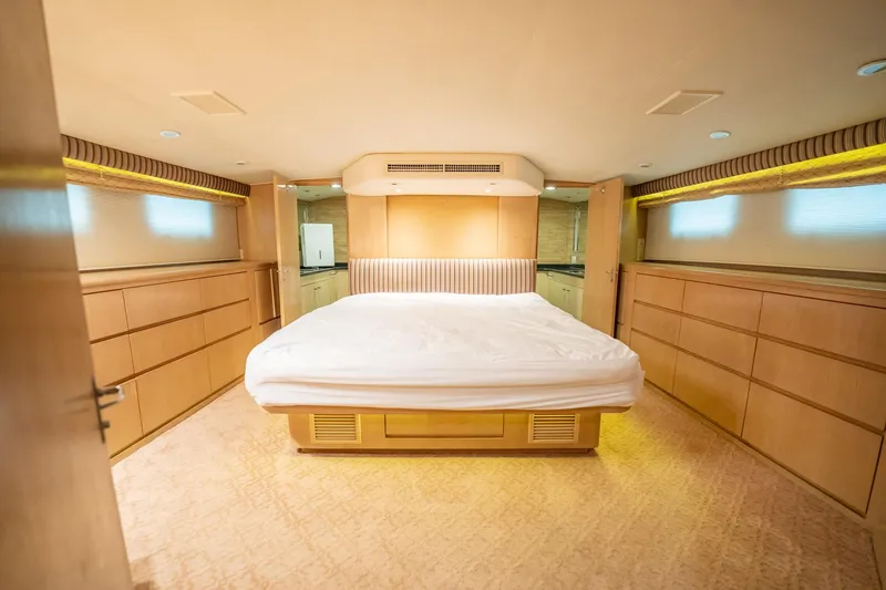 Hatt's Off Yacht Photos Pics Luxurious bedroom interior of 1998 Hatteras 74 Cockpit Motor Yacht with elegant wood finish.