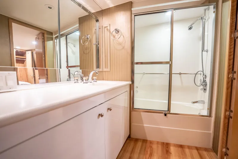 Hatt's Off Yacht Photos Pics Luxurious bathroom in 1998 Hatteras 74 Cockpit Motor Yacht with modern fixtures and wood accents.