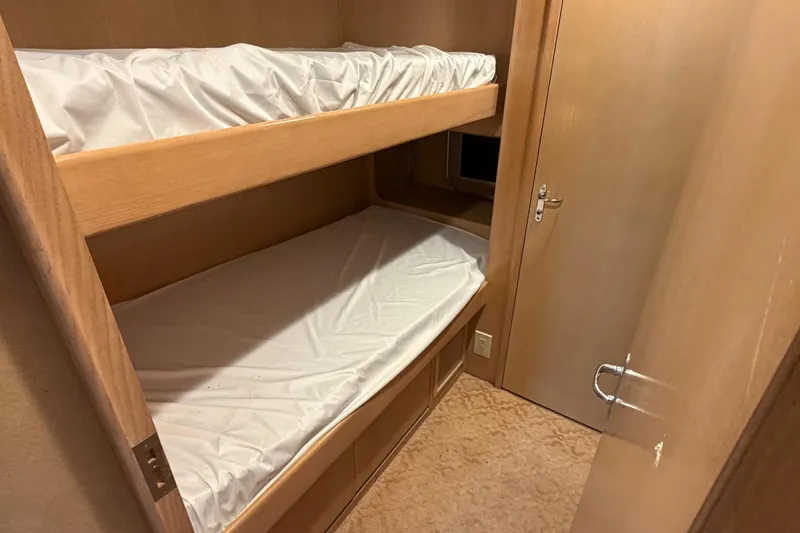 Hatt's Off Yacht Photos Pics Bunk beds in 1998 Hatteras 74 Cockpit Motor Yacht cabin, featuring wooden interior.