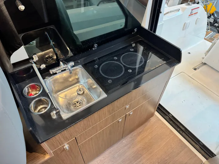  Yacht Photos Pics Compact kitchen area in a 2022 Beneteau Antares 9 boat, featuring a sink and stove.