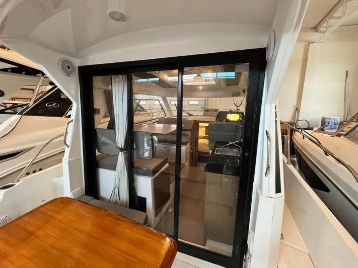  Yacht Photos Pics 2022 Beneteau Antares 9 interior view with sliding glass door and wooden table.