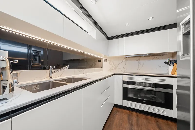 No Name Yacht Photos Pics Modern kitchen interior on 2022 Azimut Grande 27 METRI yacht, featuring sleek white cabinetry and marble accents.
