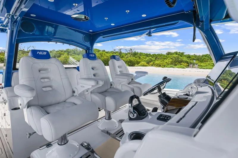 Polar II Yacht Photos Pics Luxurious 2020 HCB 53 boat interior with plush seating and advanced controls, near a scenic beach.