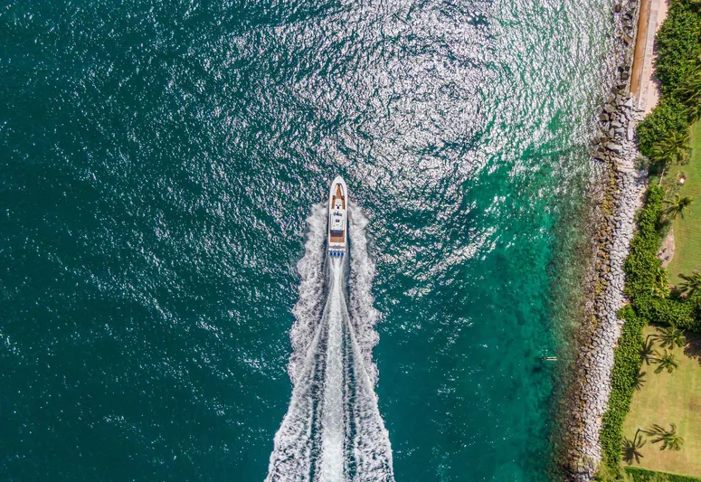Polar II Yacht Photos Pics Aerial view of 2020 HCB 53 boat cruising on turquoise water near rocky shoreline.