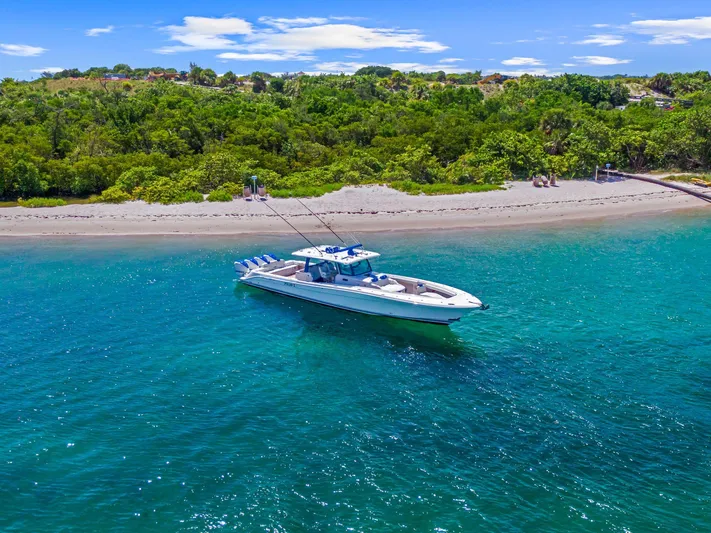 Polar II Yacht Photos Pics A 2020 HCB 53 boat on clear blue water near a lush green shoreline.