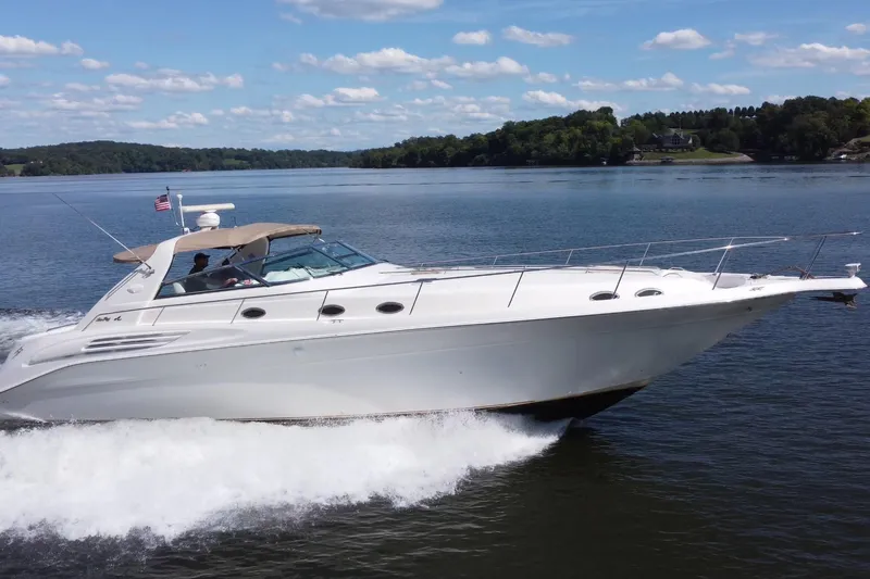  Yacht Photos Pics 1997 Sea Ray 450 Sundancer cruising on a serene lake under a clear blue sky.