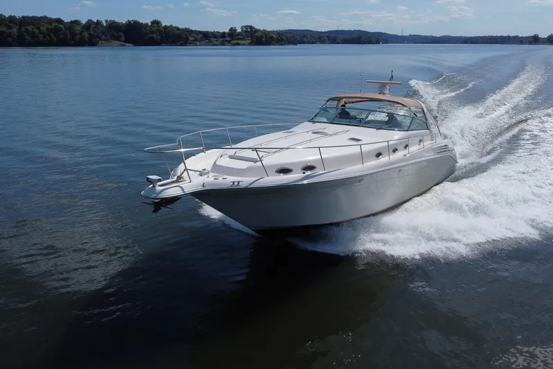  Yacht Photos Pics 1997 Sea Ray 450 Sundancer cruising on a serene lake under a clear blue sky.