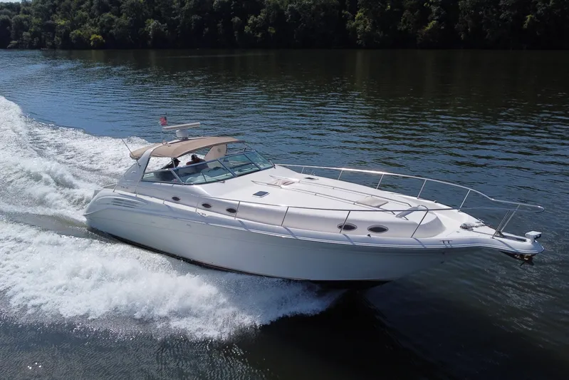  Yacht Photos Pics 1997 Sea Ray 450 Sundancer cruising on a calm lake, surrounded by lush greenery.