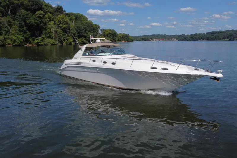  Yacht Photos Pics 1997 Sea Ray 450 Sundancer cruising on a serene lake under a clear blue sky.
