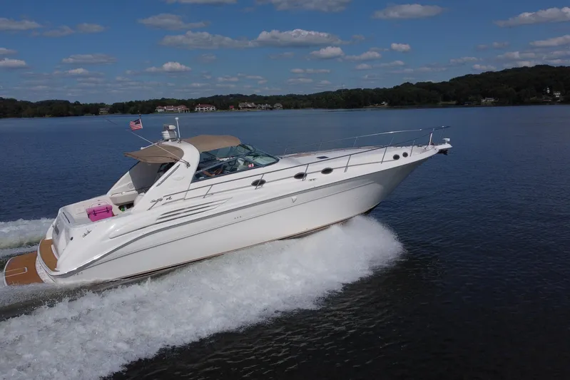  Yacht Photos Pics 1997 Sea Ray 450 Sundancer cruising on a lake under a clear blue sky.