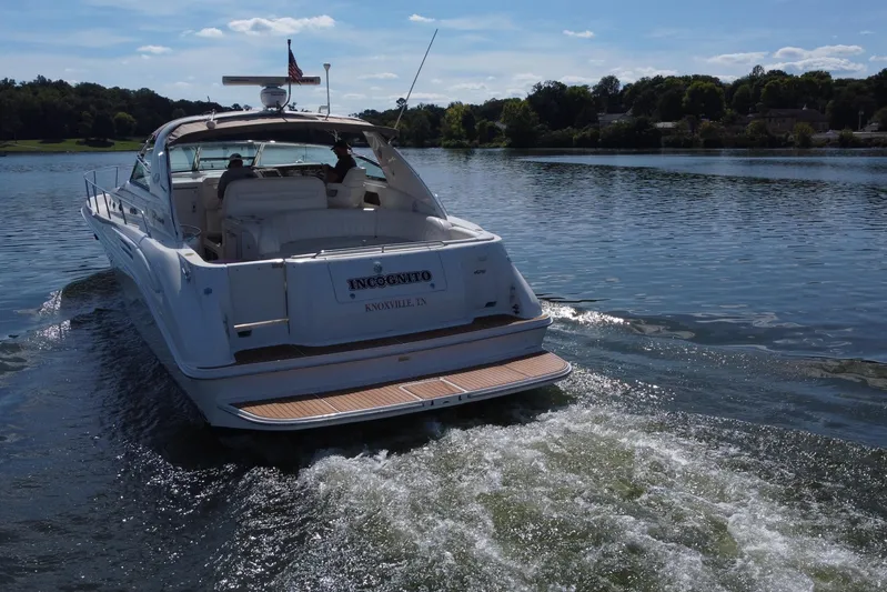 Yacht Photos Pics 1997 Sea Ray 450 Sundancer yacht cruising on a serene lake under a clear blue sky.
