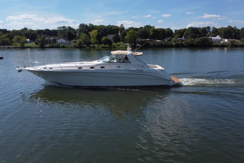  Yacht Photos Pics 1997 Sea Ray 450 Sundancer cruising on a calm lake under a clear blue sky.