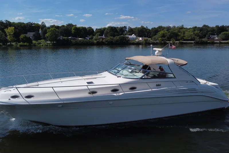  Yacht Photos Pics 1997 Sea Ray 450 Sundancer cruising on a serene lake under a clear blue sky.
