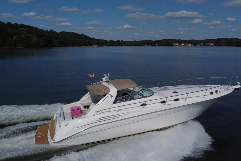  Yacht Photos Pics 1997 Sea Ray 450 Sundancer cruising on a serene lake under a clear blue sky.