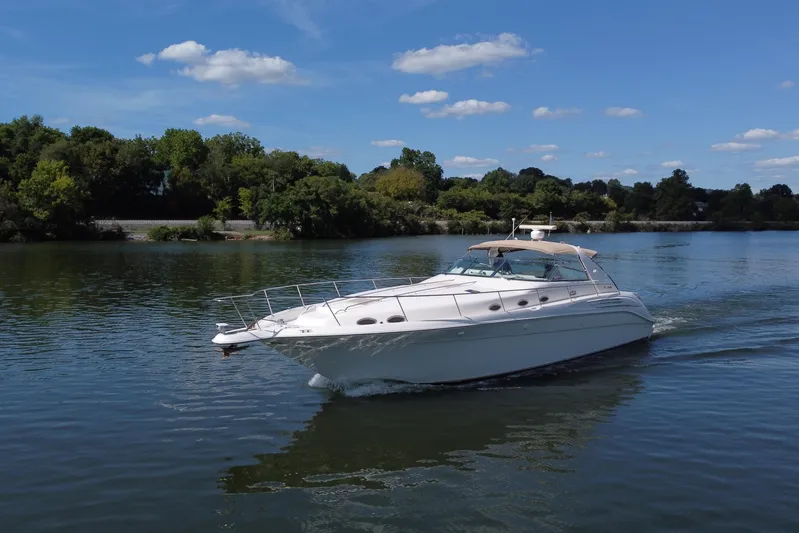  Yacht Photos Pics 1997 Sea Ray 450 Sundancer cruising on a serene lake under a clear blue sky.