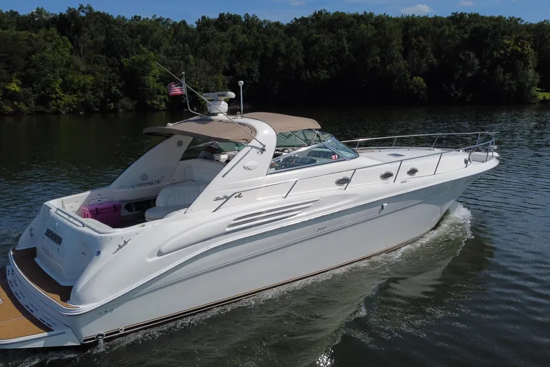  Yacht Photos Pics 1997 Sea Ray 450 Sundancer cruising on a serene lake with lush green surroundings.