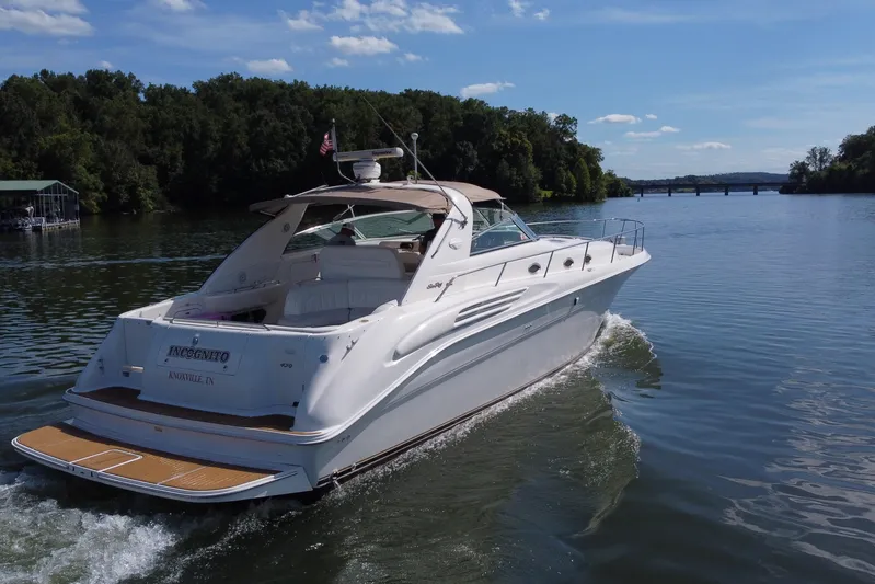  Yacht Photos Pics 1997 Sea Ray 450 Sundancer cruising on a scenic river under a clear blue sky.