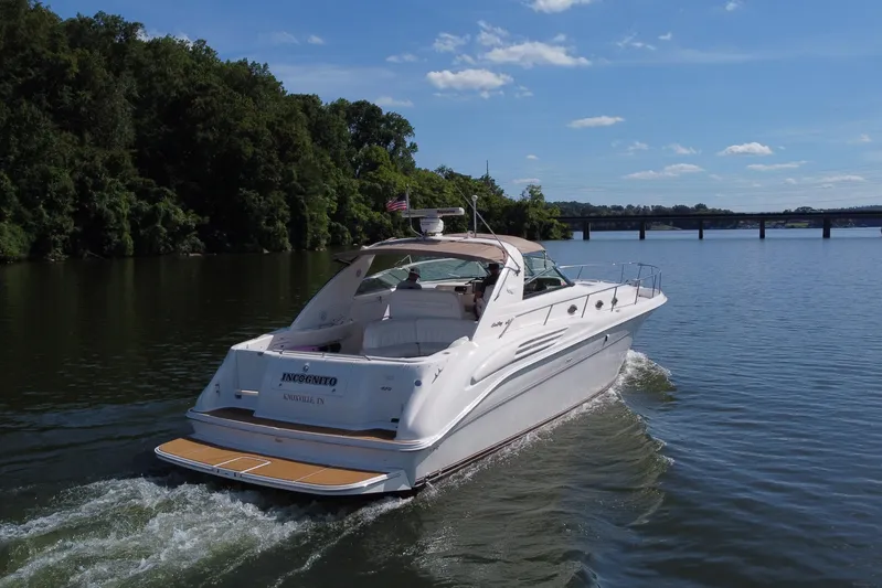  Yacht Photos Pics 1997 Sea Ray 450 Sundancer cruising on a serene river under a clear blue sky.