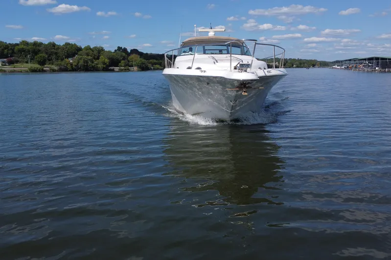  Yacht Photos Pics 1997 Sea Ray 450 Sundancer cruising on a calm lake under a clear blue sky.