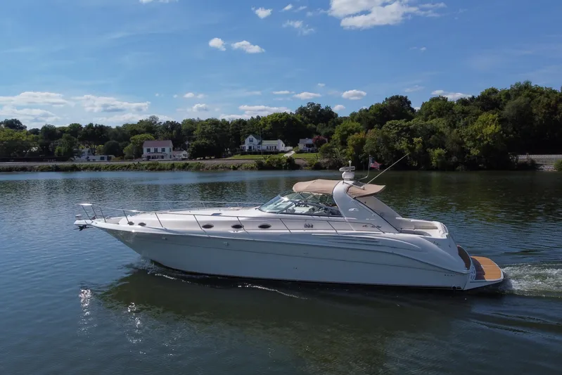 Yacht Photos Pics 1997 Sea Ray 450 Sundancer cruising on a serene lake under a clear blue sky.