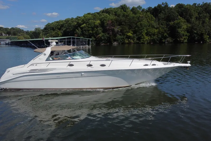  Yacht Photos Pics 1997 Sea Ray 450 Sundancer cruising on a serene lake with lush green shoreline.