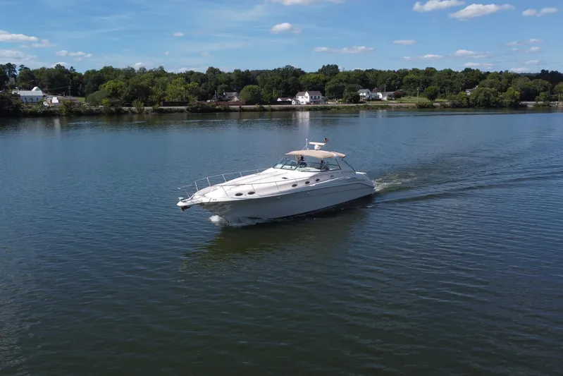  Yacht Photos Pics 1997 Sea Ray 450 Sundancer cruising on a calm lake under a clear blue sky.