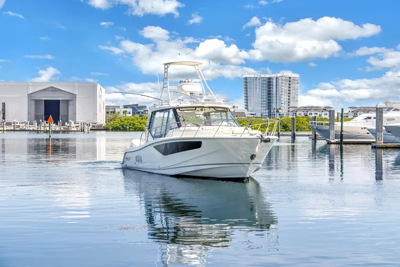 Yacht Photos Pics 2023 Boston Whaler 405 Conquest boat on calm water, with marina and buildings in background.