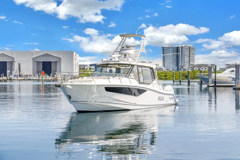  Yacht Photos Pics 2023 Boston Whaler 405 Conquest boat on calm water, with marina and buildings in background.